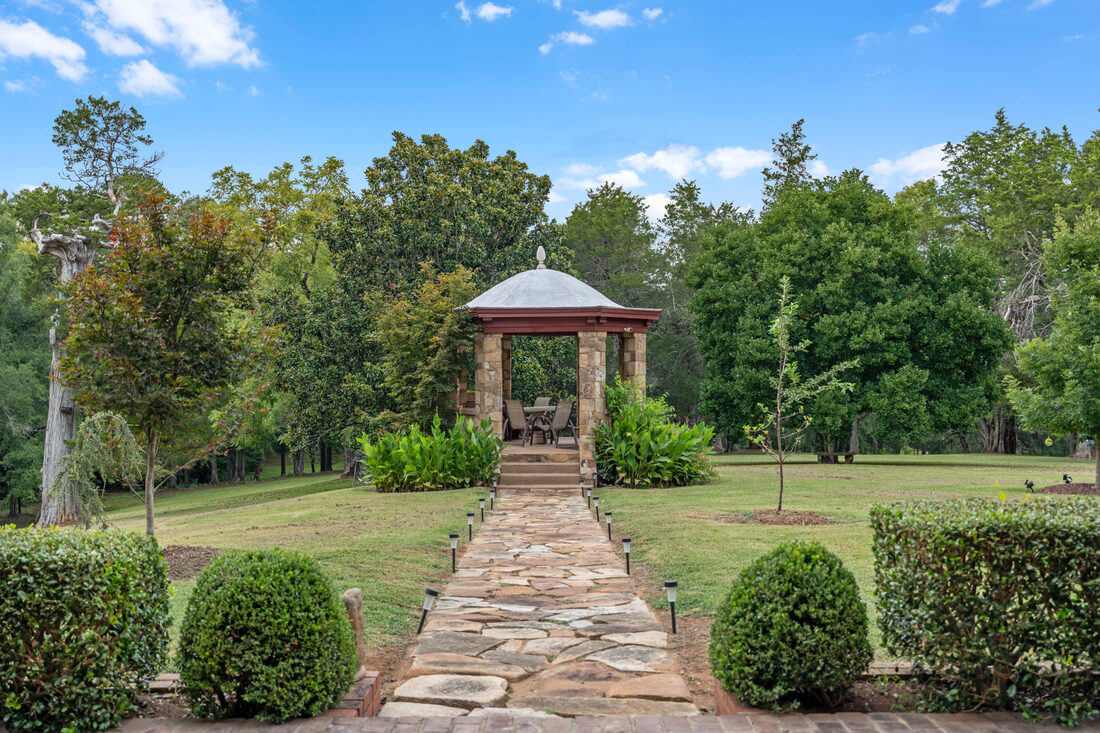 Formal boxwood gardens leading to a columned stone gazebo